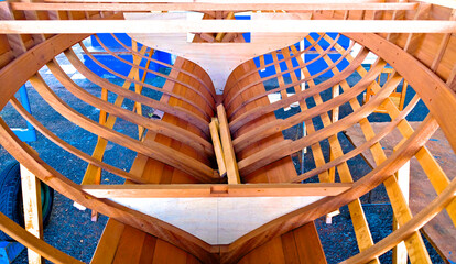 Small wooden boat in boatyard construction. Timber structure with ribs, keel, bulkheads and...