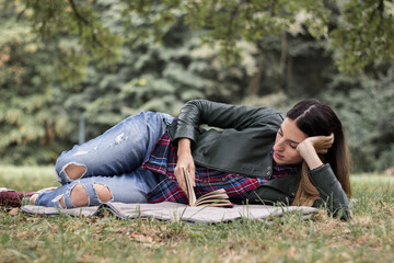 Woman reading a book while laying on the grass