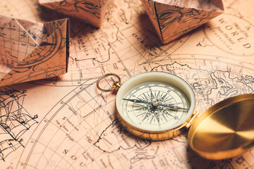 Fototapeta na wymiar Old compass and paper boats on vintage world map