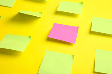 Pink paper sheet among green ones on color background. Concept of uniqueness