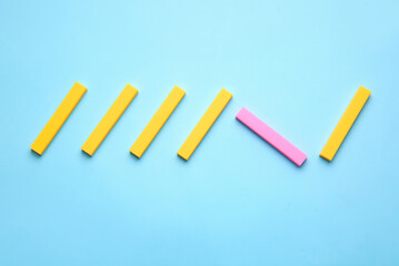 Pink eraser among yellow ones on color background. Concept of uniqueness