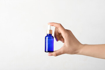 Woman with cosmetic dropper bottle on white background