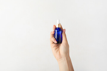 Woman with cosmetic dropper bottle on white background