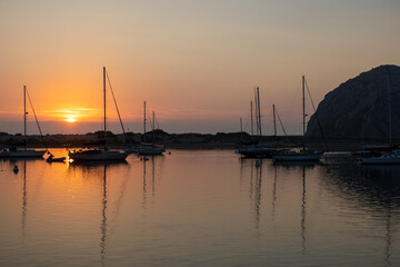 Fototapeta na wymiar A Colorful Orange Sunset in Morro Bay, California, with Boats and the Morro Rock