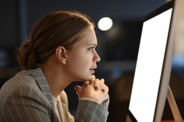 Stressed young woman working on computer in office at night