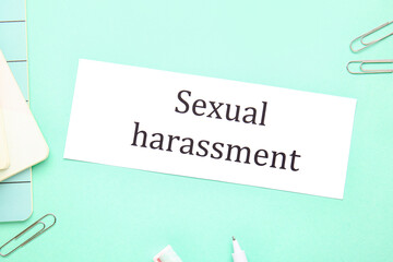 Paper with text SEXUAL HARASSMENT on color background