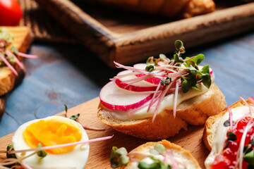 Tasty bruschetta with radish and micro green on color wooden background, closeup