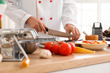 Italian chef cutting fresh basil in kitchen, closeup