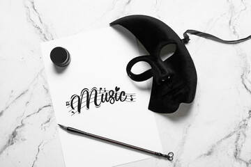 Paper with word MUSIC, brush and carnival mask on light background