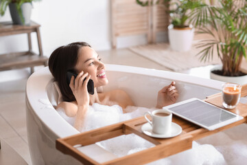 Young woman talking by mobile phone while taking bath at home