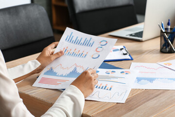 Businesswoman with charts at table in office, closeup