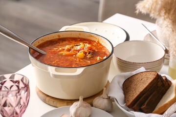 Cooking pot with delicious borscht on served table