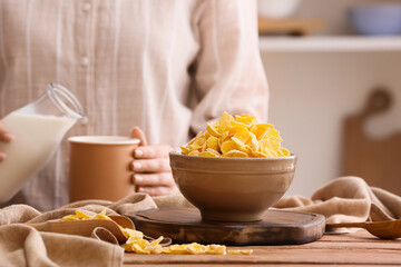 Bowl with tasty corn flakes on wooden table