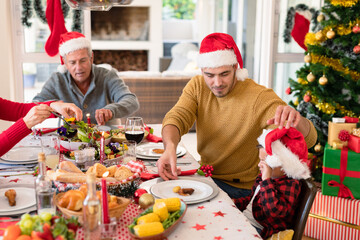 Caucasian multi generation family wearing santa hats having christmas meal