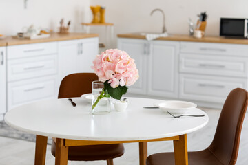 Vase with hydrangea flowers on table in kitchen