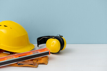 Hardhat with ear protectors and builder's supplies on color background