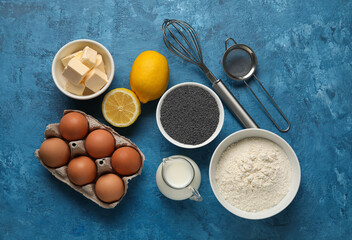 Ingredients for delicious muffins with poppy seeds on color background