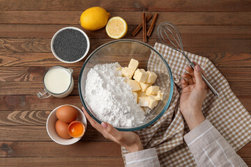 Woman preparing dough for delicious muffins with poppy seeds in kitchen