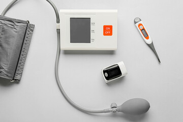 Pulse oximeter with sphygmomanometer and thermometer on light background