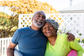 Smiling african american senior couple holding yoga mats in garden and looking at camera - Powered by Adobe