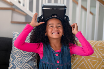Happy african american girl sitting on sofa, using vr headset and having fun