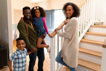 Happy african american family standing at stairs and looking at camera