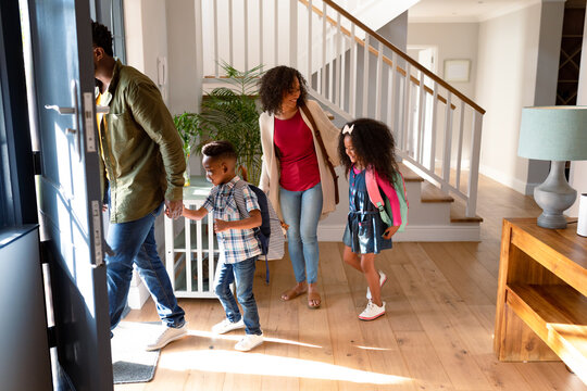 Happy african american family standing in hallway, heading to school and work