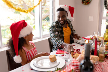 Happy african american father and daughter talking at christmas table