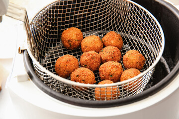Cod cutlets preparing in deep fryer on table, closeup
