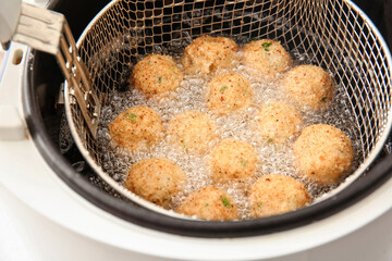 Cod cutlets preparing in deep fryer on table, closeup