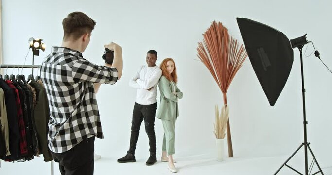 Backstage shooting of multiracial models of dark-skinned african american guy and red-haired girl photo shoot in studio