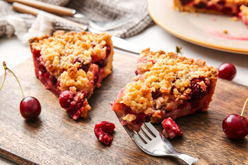 Board with pieces of tasty cherry pie on table, closeup