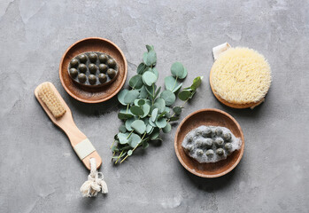 Bowls with massage soap bars, brushes and eucalyptus branches on grunge background