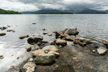 Along the West highland Way in Scotland. A view from the shore of Loch Lomond where a few stones touch the surface of the clear waters of the lake