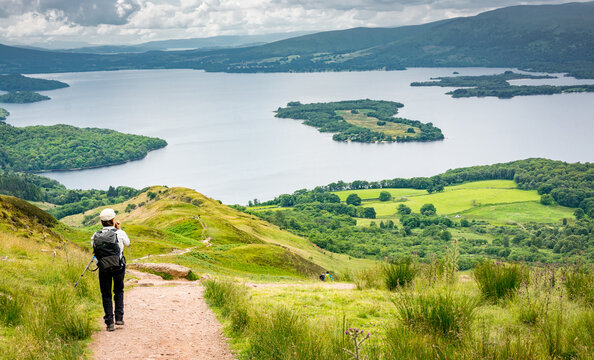 a view of Loch Lomond from the West highland Way in Scotland. A hiker walking on the path down to the lake.