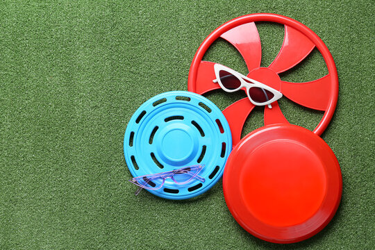 Different frisbee disks and sunglasses on color background