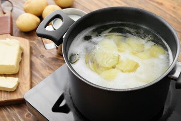 Pot with boiling potatoes on electric stove at kitchen