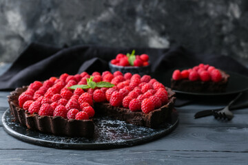 Board with tasty raspberry pie and mint on dark wooden table, closeup