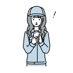 立ってスマートフォンを操作して何かに気づいて驚いた作業員の女性