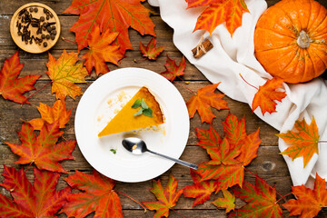 a piece of American pie on a wooden table, pumpkin and autumn leaves