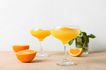 Glasses of tasty orange margarita on light background
