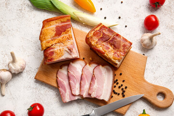 Wooden board with tasty smoked bacon and fresh vegetables on light background