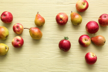Ripe pears and apples on color wooden background