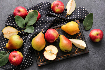 Wooden board with ripe pears and apples on dark background