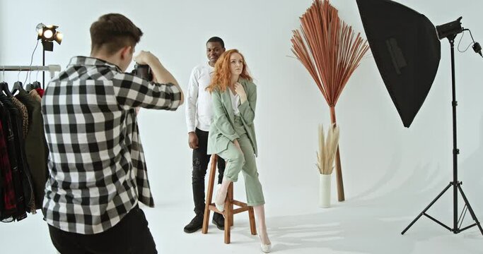 Backstage shooting of multiracial models photo shoot in the studio of a dark-skinned African American guy and a red-haired girl