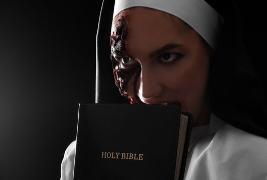 Woman dressed for Halloween as nun with Bible on dark background
