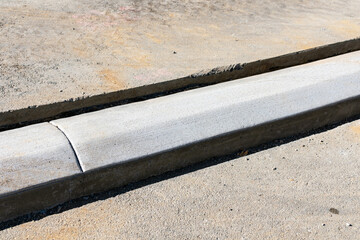 New extruded concrete curbing between asphalt and concrete sidewalk. Close up