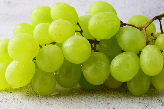 Bunch of white grapes, on stone background in gray tones.
