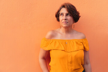 Portrait of a woman in a yellow blouse on orange wall