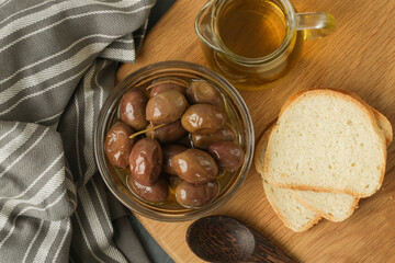 Olives, olive oil and bread on wooden rustic table.